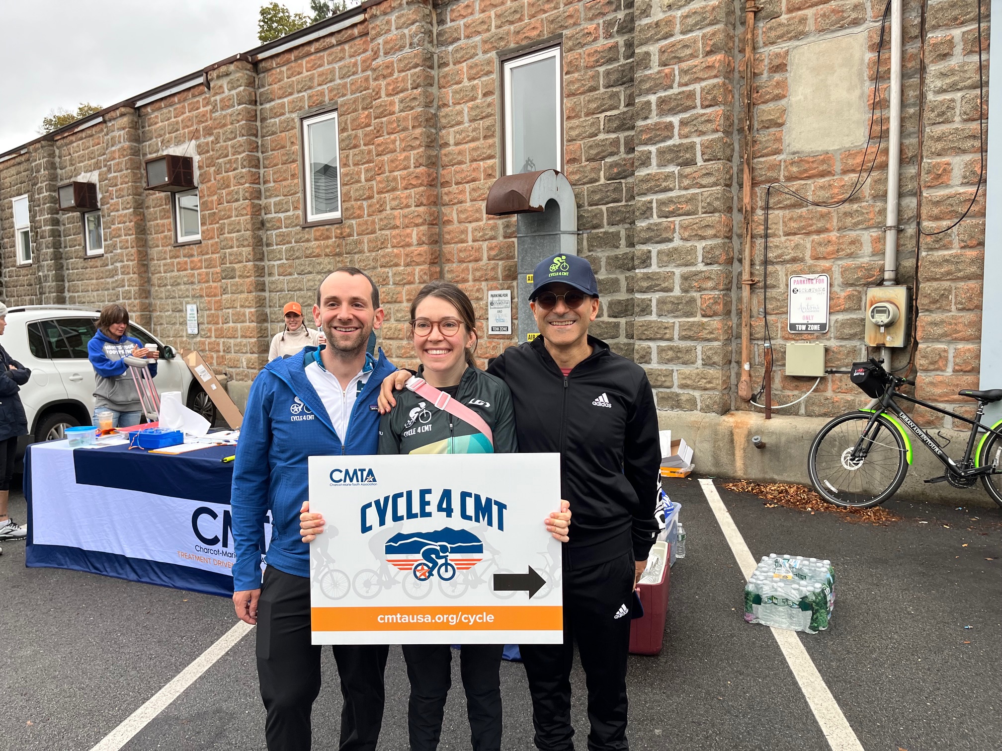 Aaron, Mary Cate, and Dr. Kleopas stand together holding a sign that reads "CMTA: Cycle 4 CMT". In this fundraiser, they successfully raised over twenty-three thousand dollars that will go directly towards funding a cure for CMT4C!
